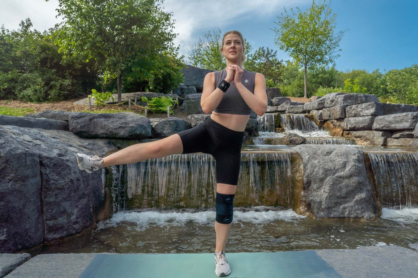 Woman performing yoga in outdoor setting wearing M-Brace Knee Wrap Compression Brace.