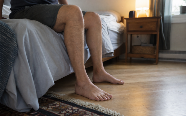 Adult placing both feet on the floor beside the bed / Adulte posant les deux pieds au sol près du lit